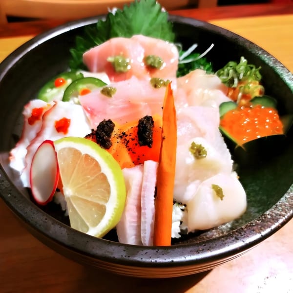A colorful Yanagi Sushi chirashi bowl with various fish, roe, and vegetables, garnished with lemon.