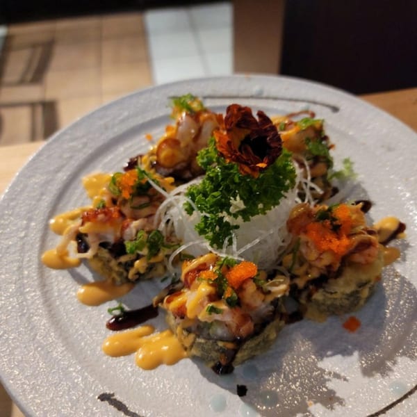Yanagi Sushi's fried sushi rolls with orange roe, green garnish, and sauces on a white plate.