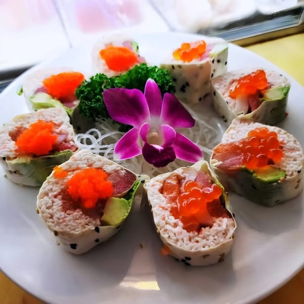 Yanagi Sushi's colorful sushi rolls with roe and avocado, garnished with a purple orchid.